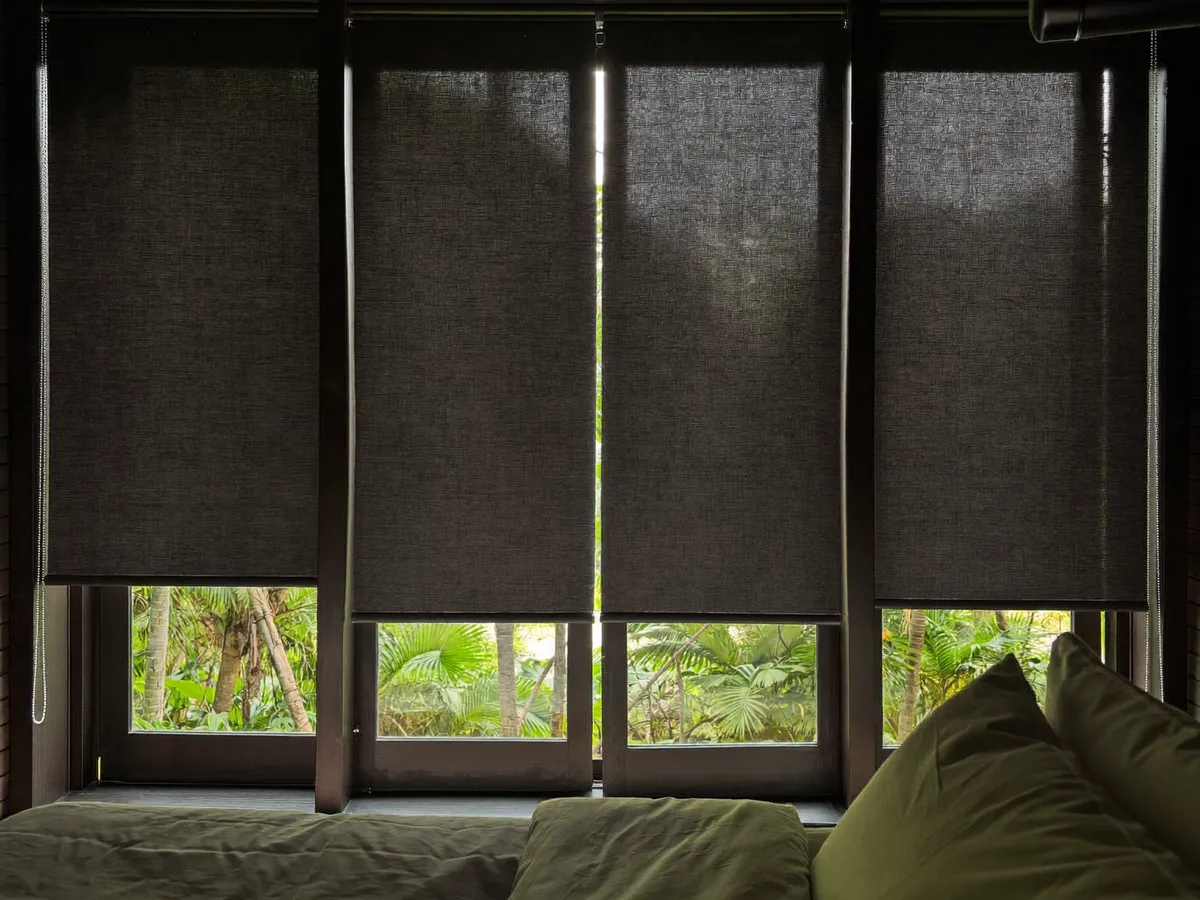 Blackout roller blinds fully closed in a tropical villa bedroom