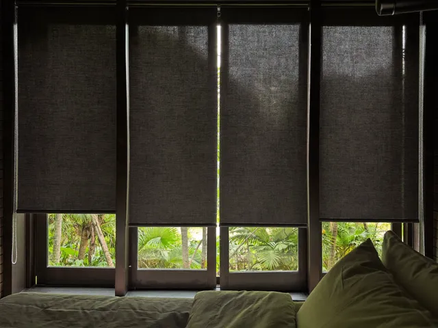 Charcoal blackout roller blinds closed in a villa bedroom